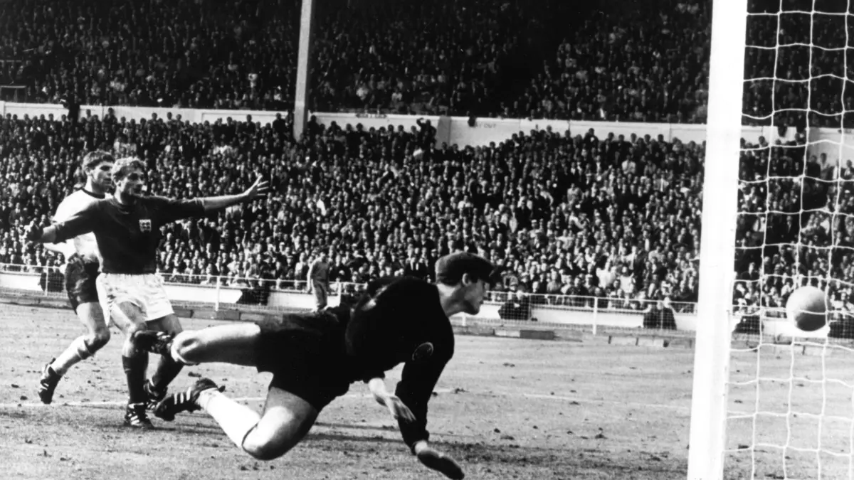 ARCHIV - 30.07.1966, Großbritannien, London: Tor oder nicht Tor im Finale Deutschland gegen England bei der Fußball-WM 1966 am 30. Juli im Londoner Wembley-Stadion. Der vom englischen Stürmer Geoff Hurst (nicht im Bild) geschossene Ball knallt von der Latte auf den Boden. Der deutsche Torhüter Hans Tilkowski (vorn) schaut sich im Hechten um, Abwehrspieler Wolfgang Weber (l) und der jubelnde englische Stürmer Roger Hunt schauen zu. (zu "Ex-Nationaltorwart Hans Tilkowski gestorben") Foto: -/dpa +++ dpa-Bildfunk +++