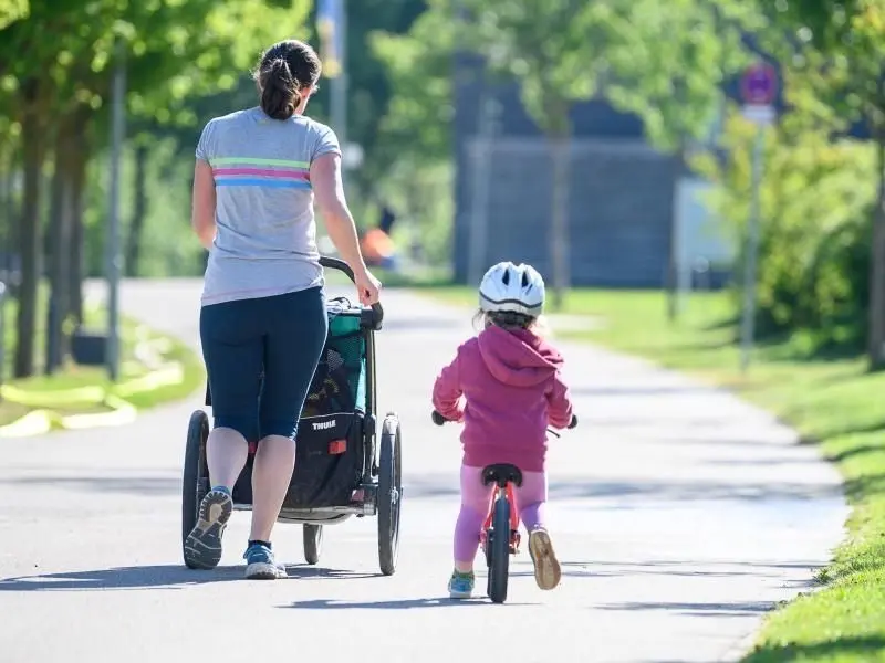Eine Frau joggt mit ihrer Tochter, die eigentlich in der Kita wäre.