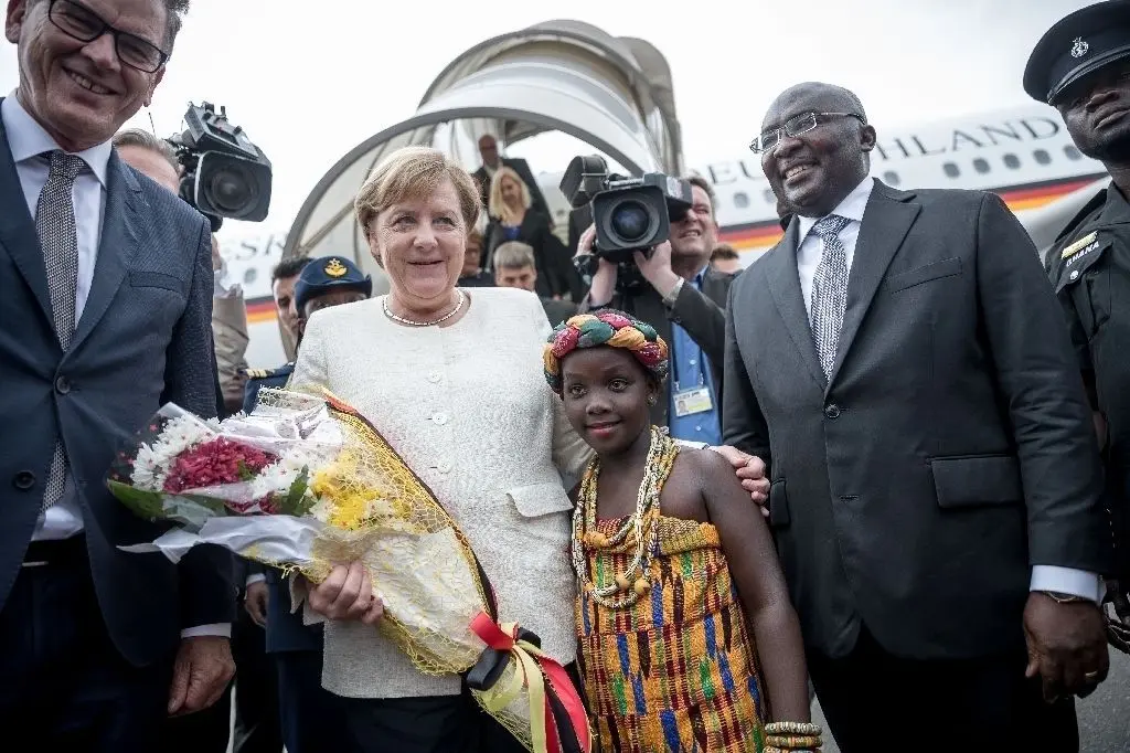 Bundeskanzlerin Angela Merkel (CDU) wird am Flughafen von Vizepräsident Mahamudu Bawumia (r.) zusammen mit Gerd Müller (CSU), Entwicklungsminister (l.), von einem Blumenkind begrüßt. Ghana ist die zweite Station der dreitägigen Afrikareise der Kanzlerin.