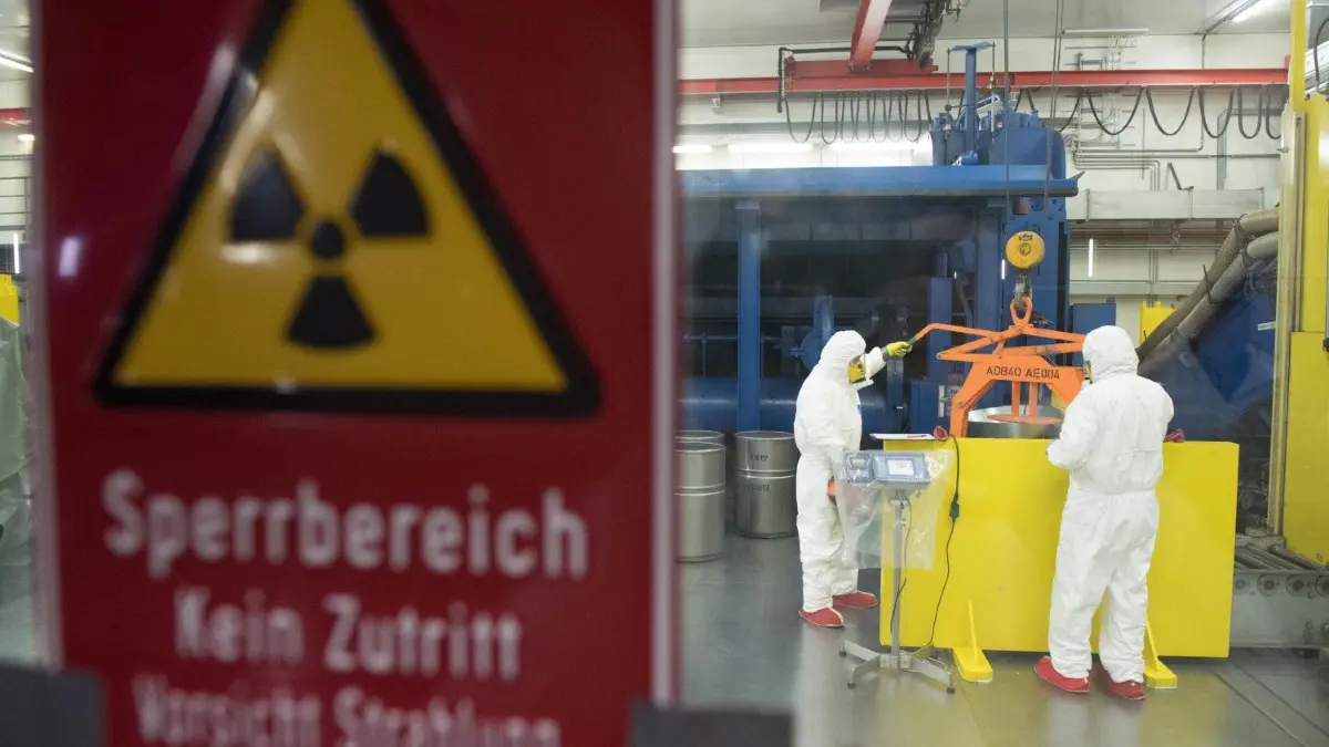 Mitarbeiter arbeiten in einem Zwischenlager für Atommüll.
ARCHIV - 11.12.2017, Mecklenburg-Vorpommern, Lubmin: Mitarbeiter des «Zwischenlager Nord» (ZLN) arbeiten im Zwischenlager auf dem Gelände des «Entsorgungswerk für Nuklearanlagen» (EWN) Lubmin in einer Zerlegungskabine. Die Bundesgesellschaft für Endlagerung legt den Zwischenbericht mit Teilgebieten für die Endlagersuche vor. Foto: picture alliance / Stefan Sauer/dpa +++ dpa-Bildfunk +++