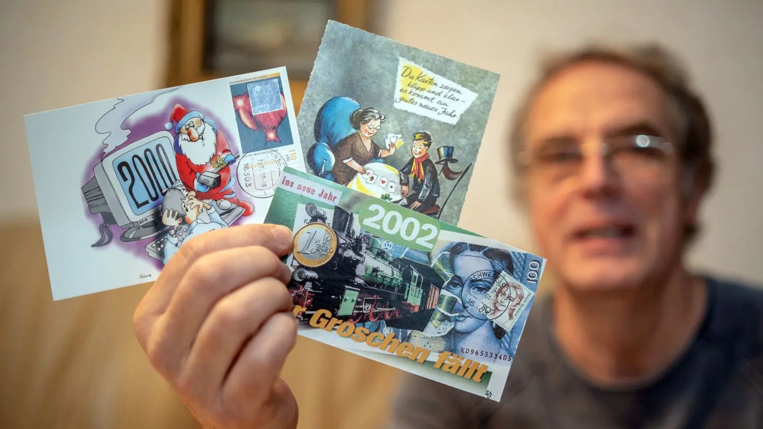 Aufgefächert in der Hand: Wolfgang Bandelmann zeigt drei Neujahrskarten aus seiner einzigartigen Sammlung, die Hunderte Exemplare umfasst.