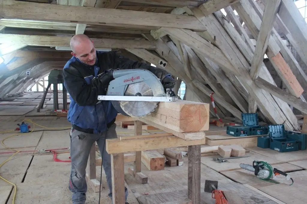 Letzter Schnitt für Balken aus Kiefer: Zimmerer Andreas Friedrich sägt das Holz so zu, dass es sich in das vorhandene Gebälk im Dachstuhl des Jagdschlosses einfügt. Seit November sind Handwerker aus Thüringen vor Ort, um die Konstruktion zu sanieren.