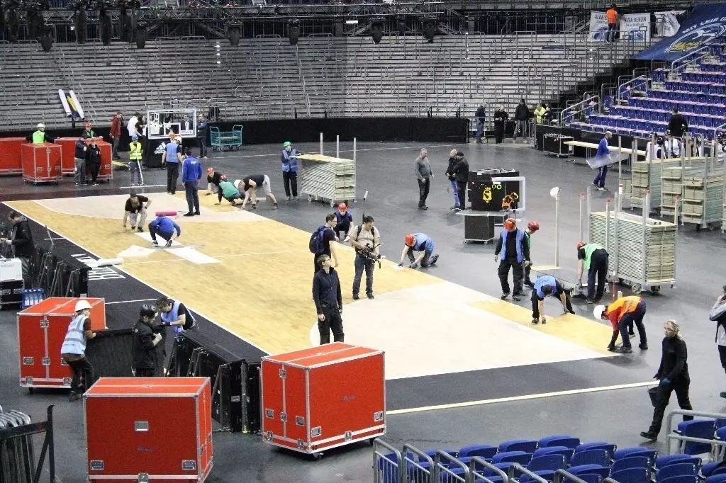 Vor dem Basketball-Pokalfinale legen Mitglieder der Umbau-Crew Parkett für die Spielfläche aus.