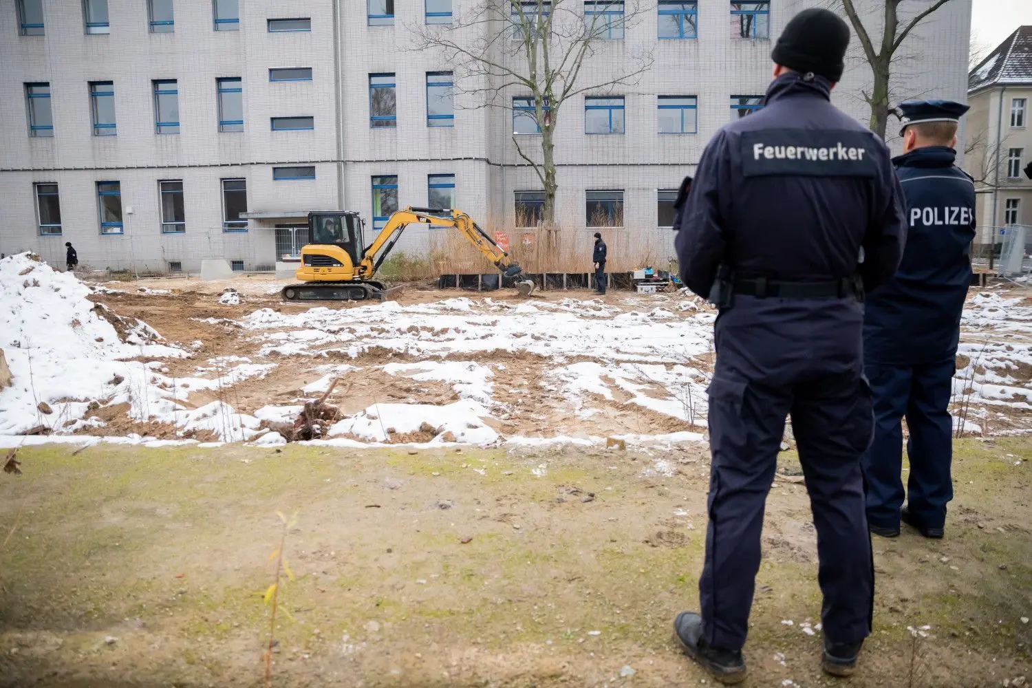 Innerhalb des Sperrkreises mussten die Menschen in Berlin-Gesundbrunnen ihre Wohnungen verlassen. Die Weltkriegsbombe wurde vor Ort entschärft. Ein Feuerwerker des Kampfmittelräumdienstes der Berliner Polizei und ein weiterer Polizist beobachten, wie ein Bagger die Bombe auf dem Gelände des Jüdischen Krankenhauses Erdschichten über der Bombe abträgt.
