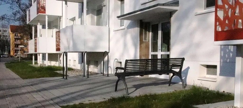 Tragen zum Wohlfühlen bei: Vor den Hauseingängen laden Sitzbänke zum Verweilen ein, die Bügelfahrradständer sind besonders praktisch (Bild oben). Transparente Windschutzscheiben gewähren freie Sicht auf die Balkone (rechts).