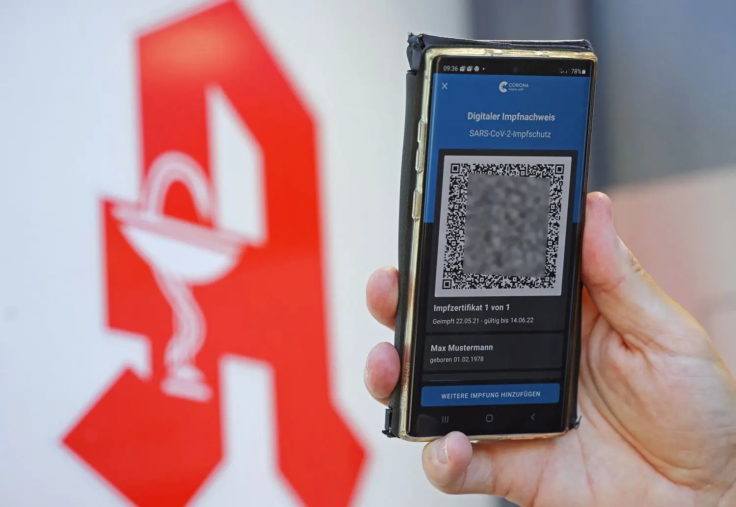 Der digitale Impfnachweis ist vor dem Apotheken-Logo auf einem Smartphone zu sehen.