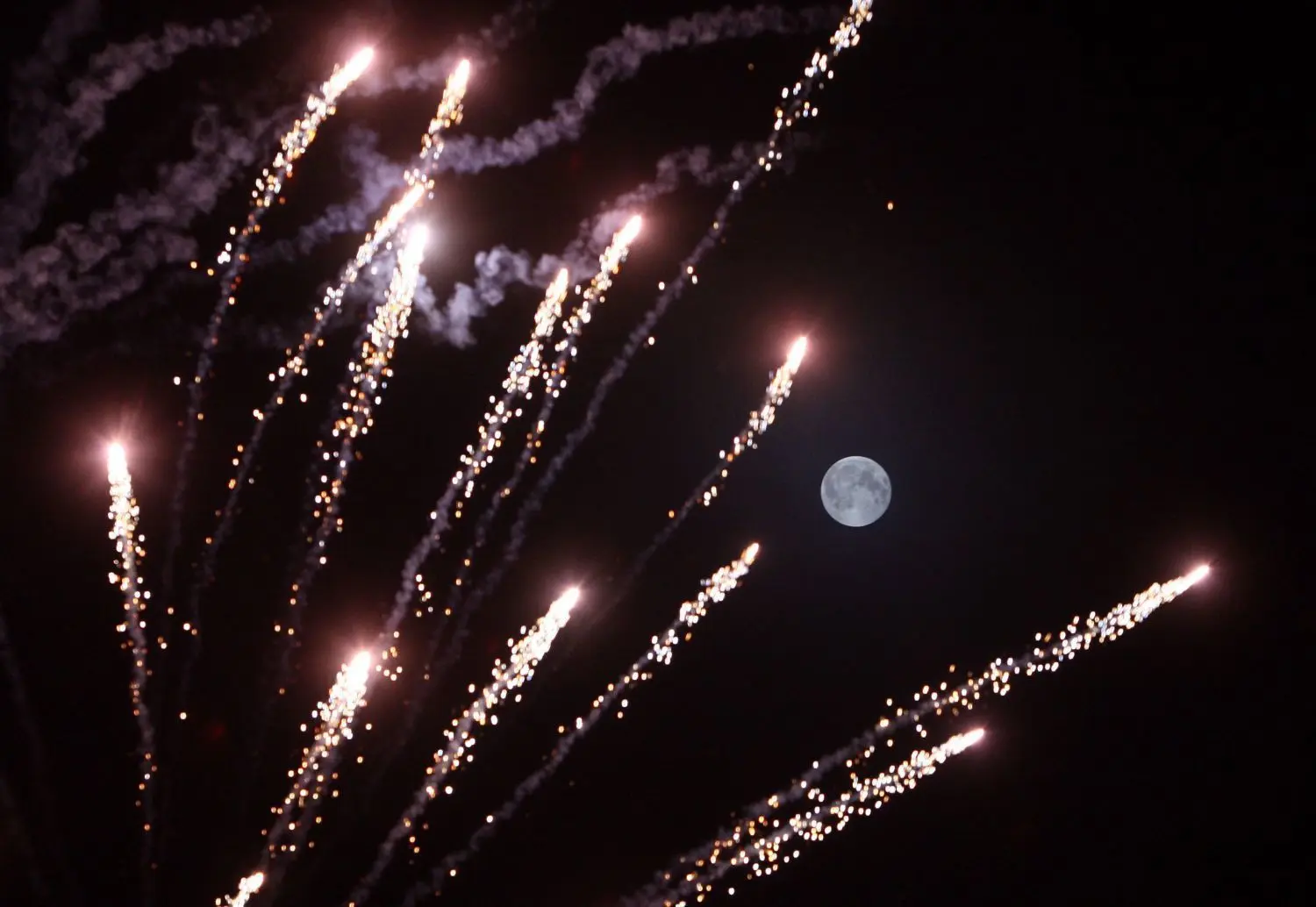 Feuerwerkskörper explodieren um Mitternacht vor dem Vollmond am Himmel (Archivbild).