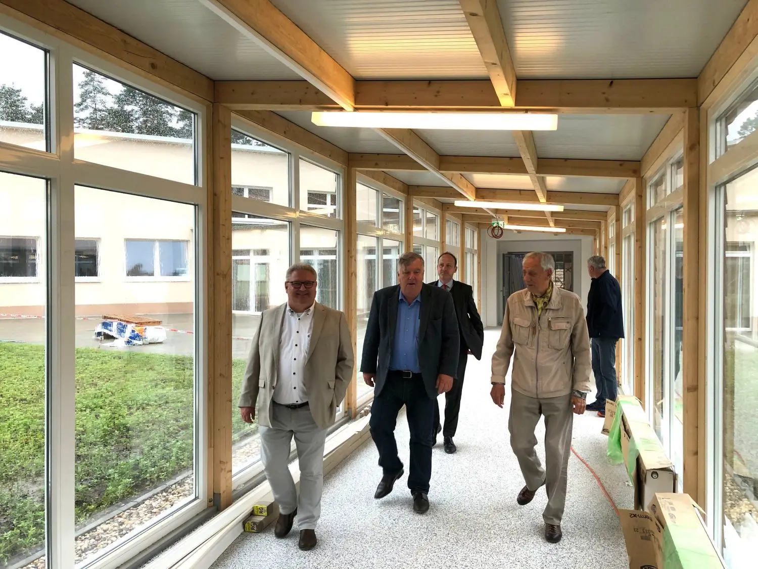 Regengeschützter Baustellenrundgang: Investor Peter Fritz (r.), Landrat Gernot Schmidt (M.) und der Vorsitzende der Stadtverordnetenversammlung Strausberg Steffen Schuster (l.) in einem Verbindungsgang der künftigen Kindernachsorgeklinik.