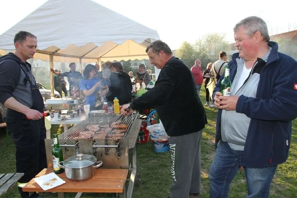 Osterfeuer auf der Festwiese in Lietzen: Unterstützt von Daniel Kreft (l.) und beobachtet von Bürgermeister Frank Kasper (r.) hatte Andreas Alsdorf am Grillstand der Feuerwehr gut zu tun.