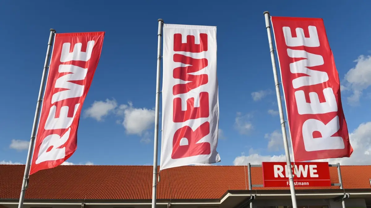 Der Kölner Handelsriese lässt das russische Sortiment auslaufen.
ARCHIV - 25.02.2020, Hessen, Volkmarsen: Fahnen mit dem Logo des Lebensmitteleinzelhändlers Rewe wehen vor einer Filiale. Der Kölner Handelsriese Rewe will sein Standbein im Ausland stärken. (zu dpa «Handelsriese Rewe steckt Milliarden in Auslandsexpansion») Foto: Uwe Zucchi/dpa +++ dpa-Bildfunk +++
