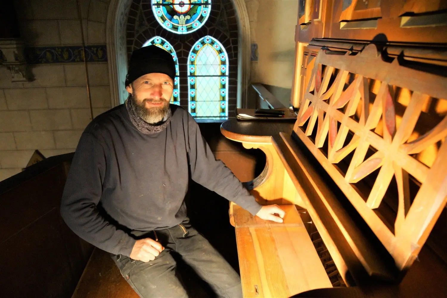 Orgelbauer Tobias Schramm sitzt vor dem leeren Spieltisch der Orgel in Gottberg. Die Klaviatur hat er bereits aufgearbeitet.