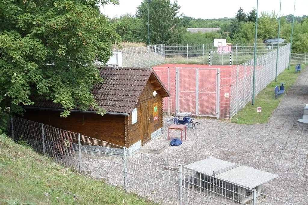 Frisch gestrichen: Blick auf das Holzhaus zur Ausgabe der Spielgeräte - nicht nur für Minigolf und Tischtennis, sondern auch für Fuß-, Basket- und Federball. Auf dem dahinterliegenden roten Platz kann gespielt werden.