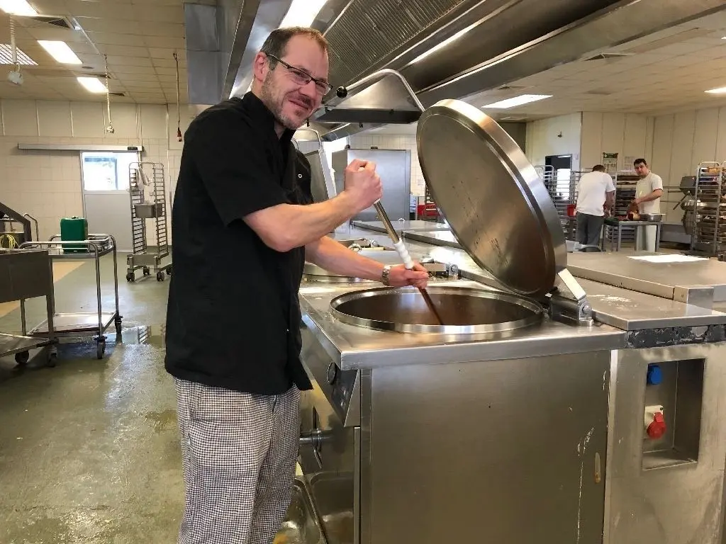 Bereitet täglich das Essen zu: Diätkoch Frank Eue rührt in einem der riesigen Edelstahlbehälter in Löwenberg die Suppe an. Pünktlich soll das Essen an jedem Tag auf den Tisch kommen.