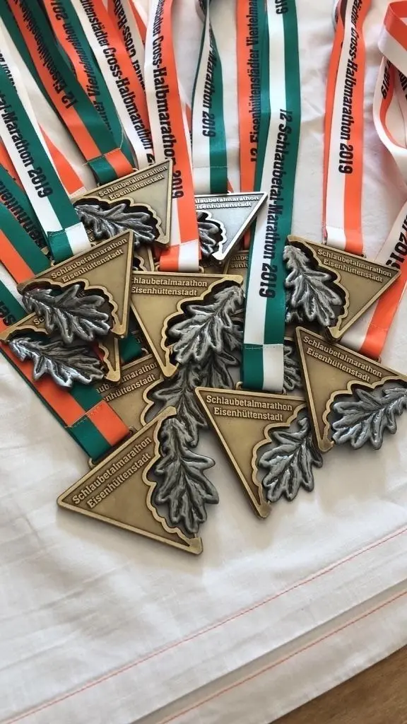 Hingucker: Die Medaillen für die Teilnehmer des Schlaubetal-Marathons (oben) sind eine tolle Erinnerung. Doch diese gibt es erst nach dem Zieleinlauf. Vorab werden die Startbeutel verteilt, die am Mittwoch in der Inselhalle gepackt wurden (r.).