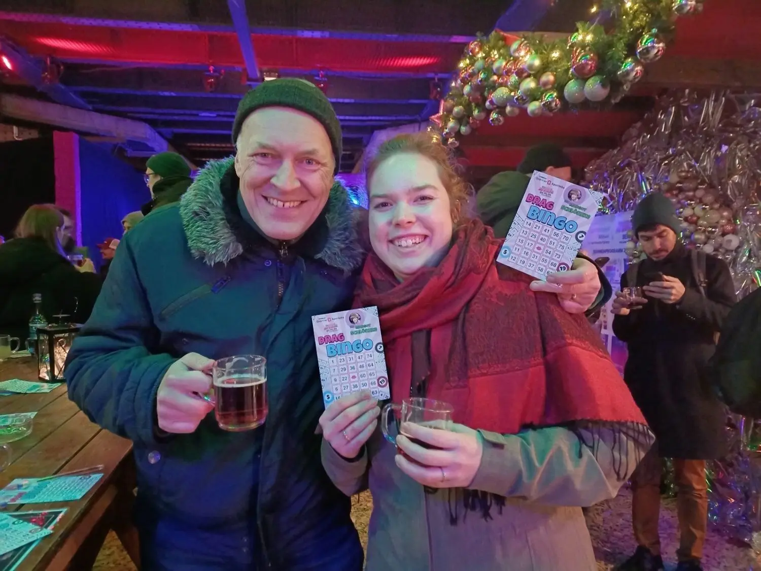 Die Arbeitskollegen Oliver (53) und Laura (26) sind direkt nach Feierabend auf den „LGBTIQ Winterdays“-Weihnachtsmarkt nach Berlin-Schöneberg gekommen, um Glühwein zu trinken und beim Drag Bingo mitzuspielen.