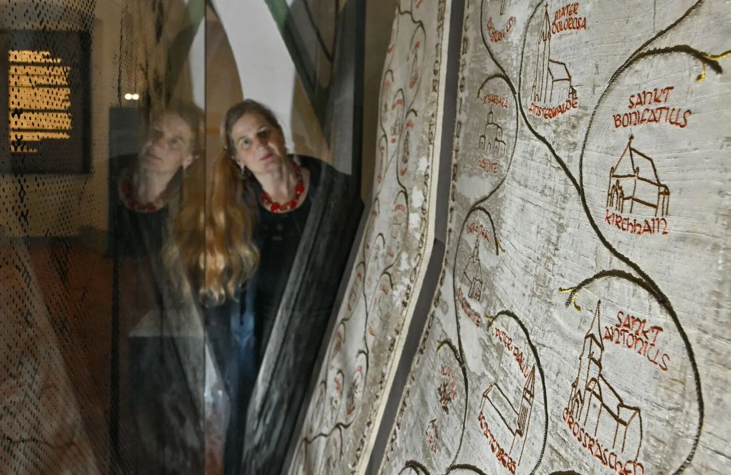Restauratorin Dorothee Schmidt-Breitung betrachtet in der Dauerausstellung des Klostermuseums im Kreuzgang des Klosters Neuzelle Fallschirmseide, die mit dem Neuzeller Wallfahrtslied bestickt ist. Ab 1. April sollen sich Gäste noch besser orientieren und informieren können.