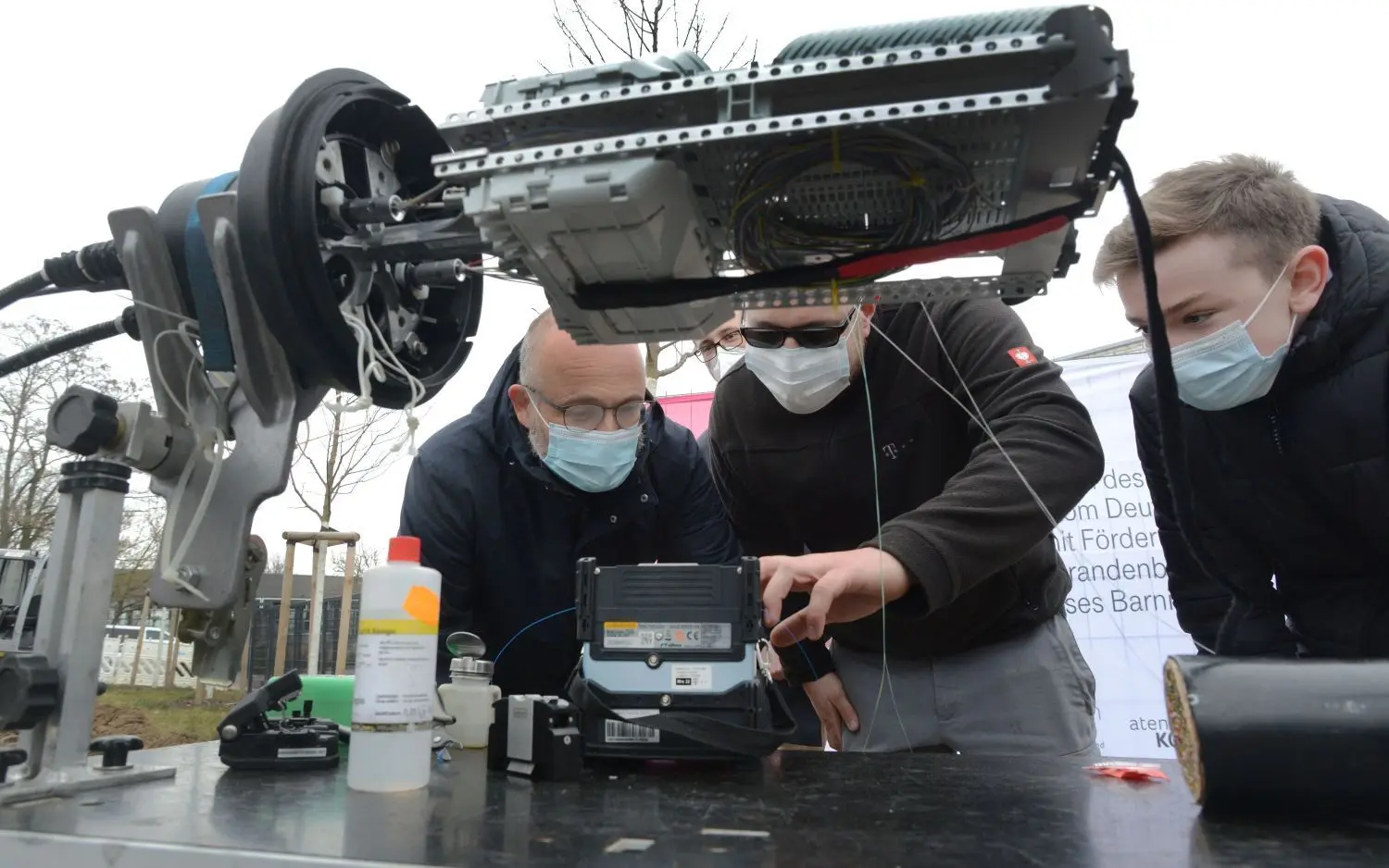 Erklärungen am Objekt: Barnims Landrat Daniel Kurth, Telekom-Techniker Nico Schoppa und Schüler Ian Wohlgemuth aus der Klasse 8d in Schwanebeck (v.l.) schauen sich die dünnen Glasfaserstränge an, die einem Menschenhaar gleichen. Sie eröffnen ganz neue Möglichkeiten.