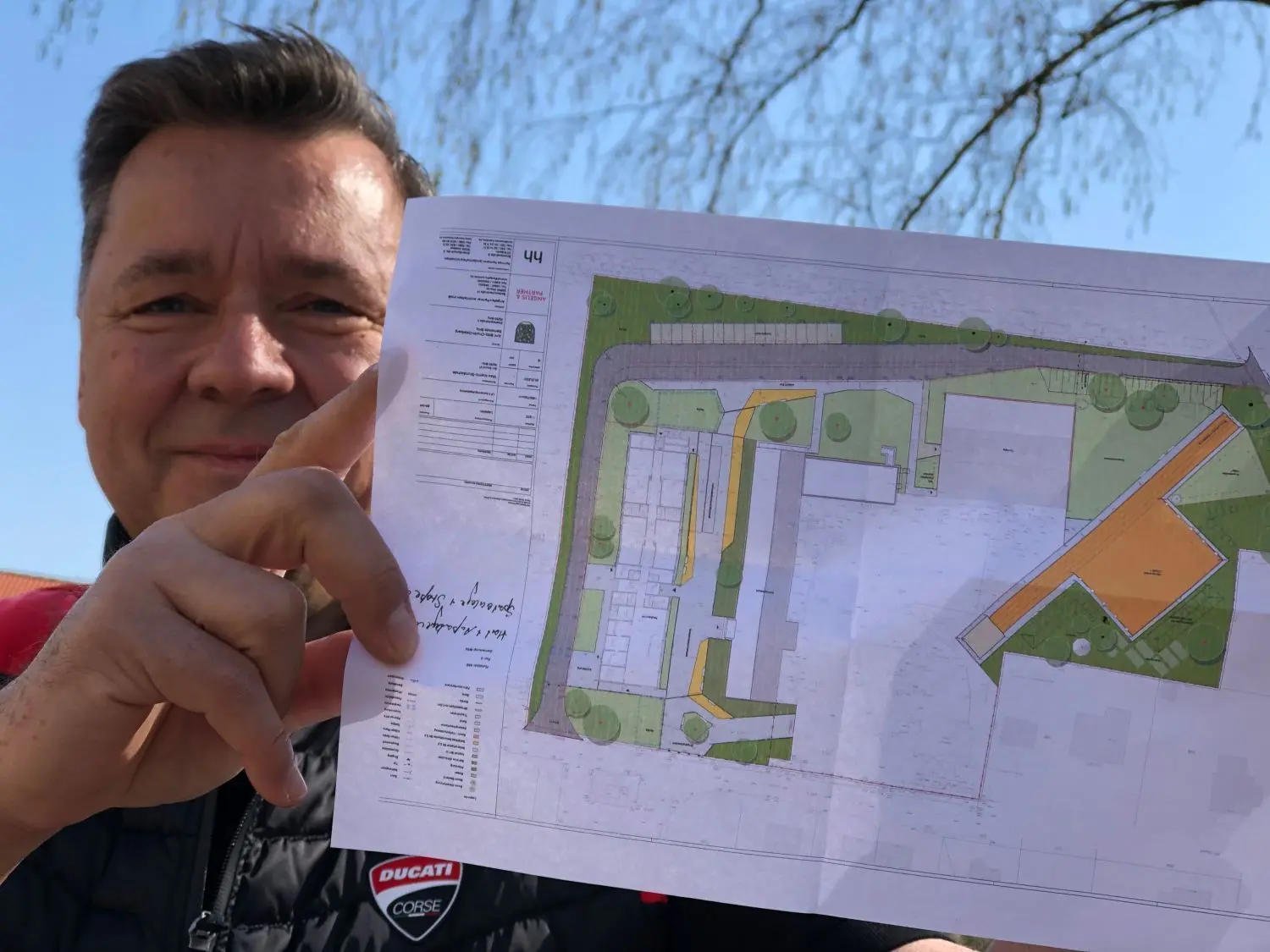 So ist der Plan: Bürgermeister André Guse zeigt eine Skizze des Areals. Zu sehen ist oben und ganz links in grau die neue Straße sowie links in weiß der Hort. Ganz rechts sind Teile der Außenanlage mit neuer diagonaler 100-Meter-Laufbahn abgebildet.
