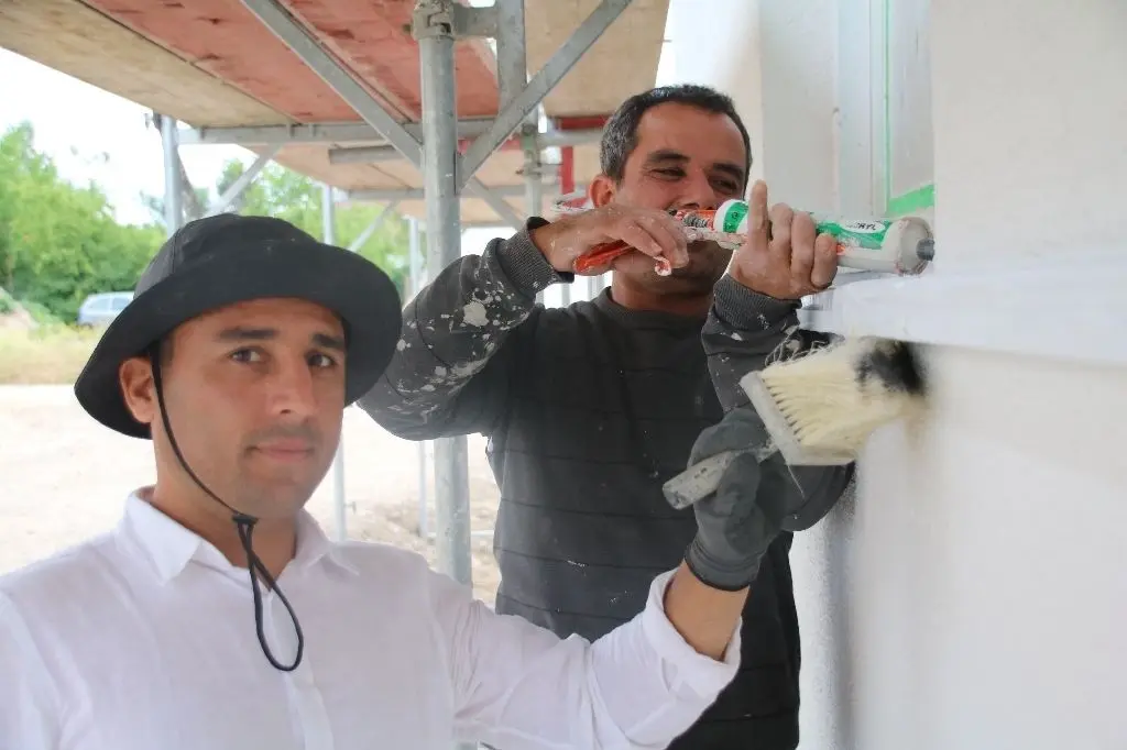 Obaidullah Raofi (l.) und Metin Özgul erledigen letzte Arbeiten an der Fassade eines Hauses des ersten Bauabschnitts.