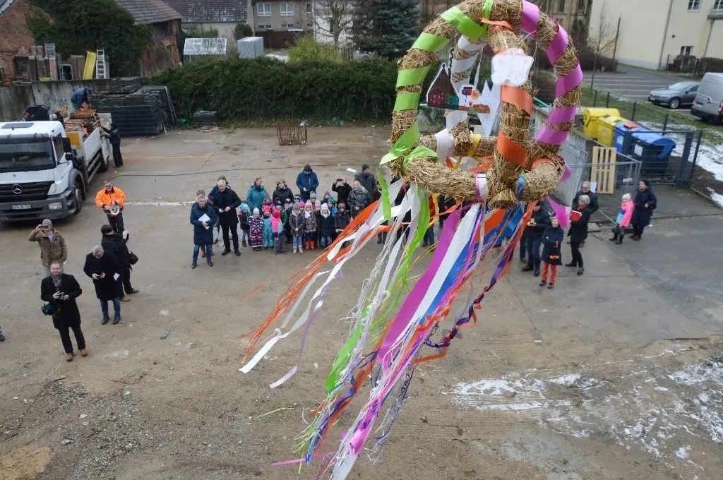 Schmuckstück: Kita-Kinder haben den Richtkranz mit selbst gebastelten Häuschen und einem Schmetterling sowie den bunten Bändern mit ihren Erzieherinnen selbst angefertigt.