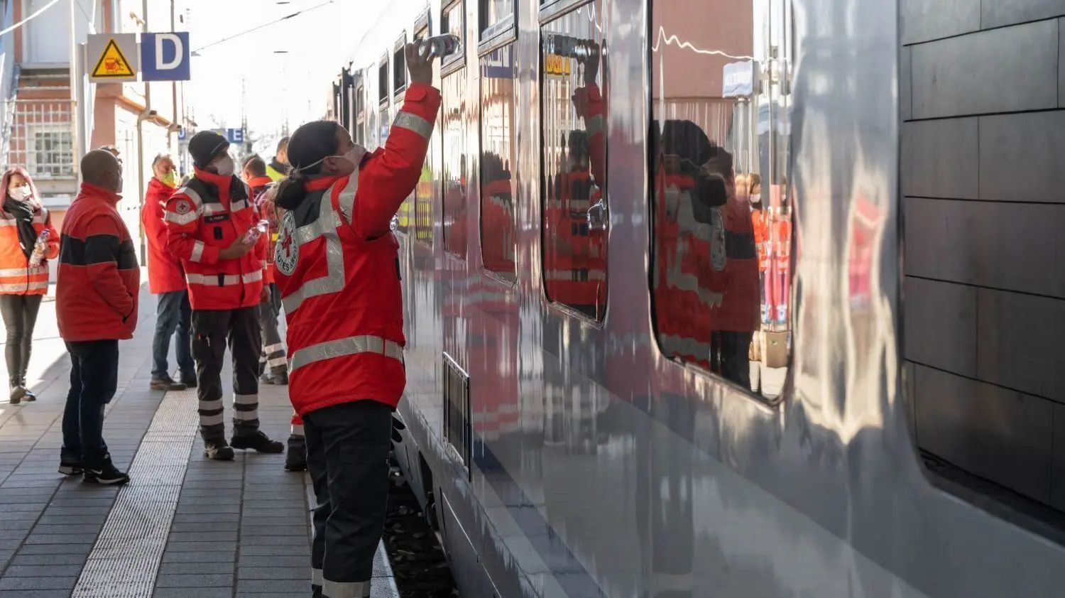 Mitarbeiter und Ehrenamtliche vom DRK reichen am Bahnhof in Frankfurt (Oder) aus der Ukraine Flüchtenden Wasser.
