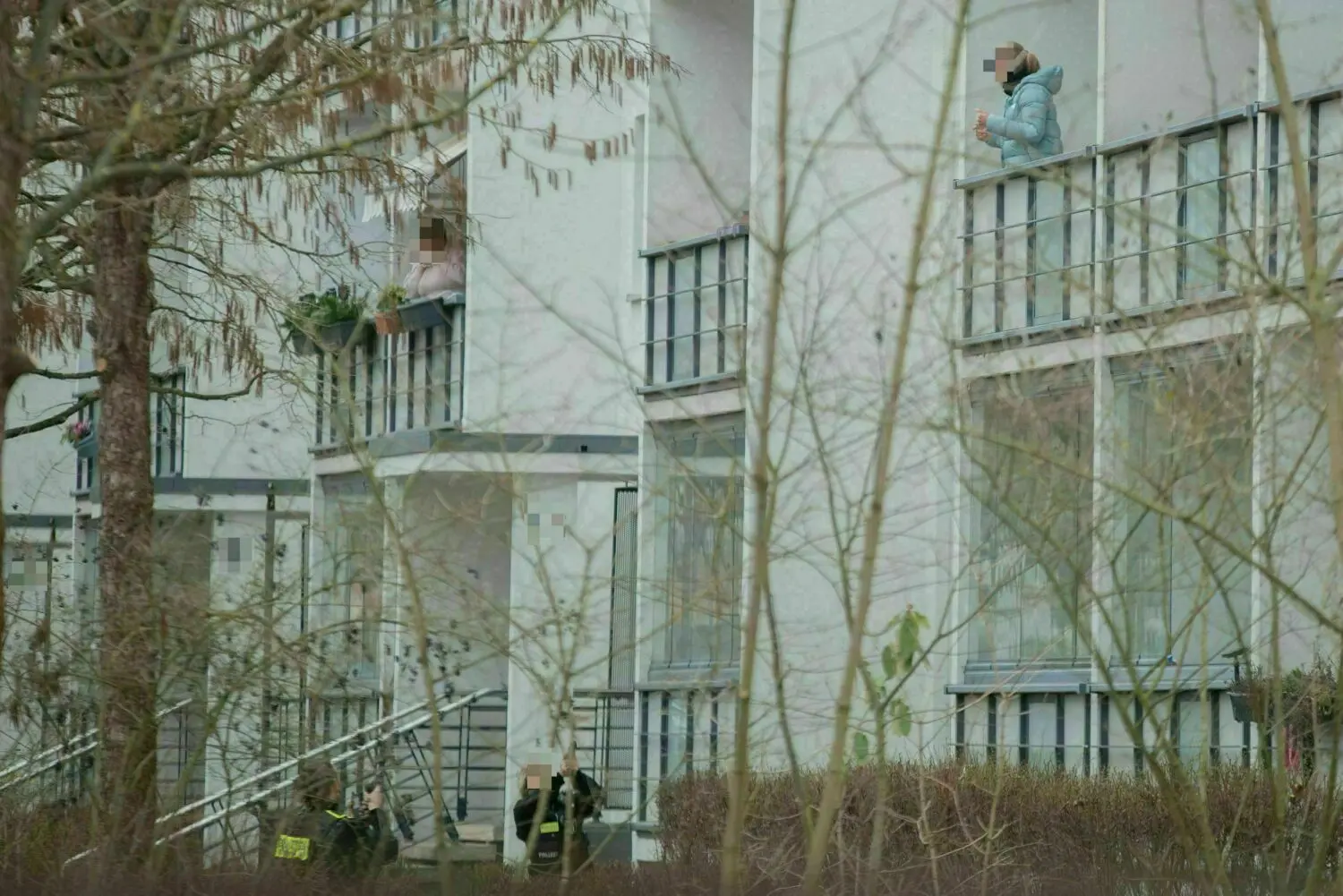 Die Frau steht auf dem Balkon ihrer Wohnung. Beamten richten ihre Dienstwaffe auf die Frau.