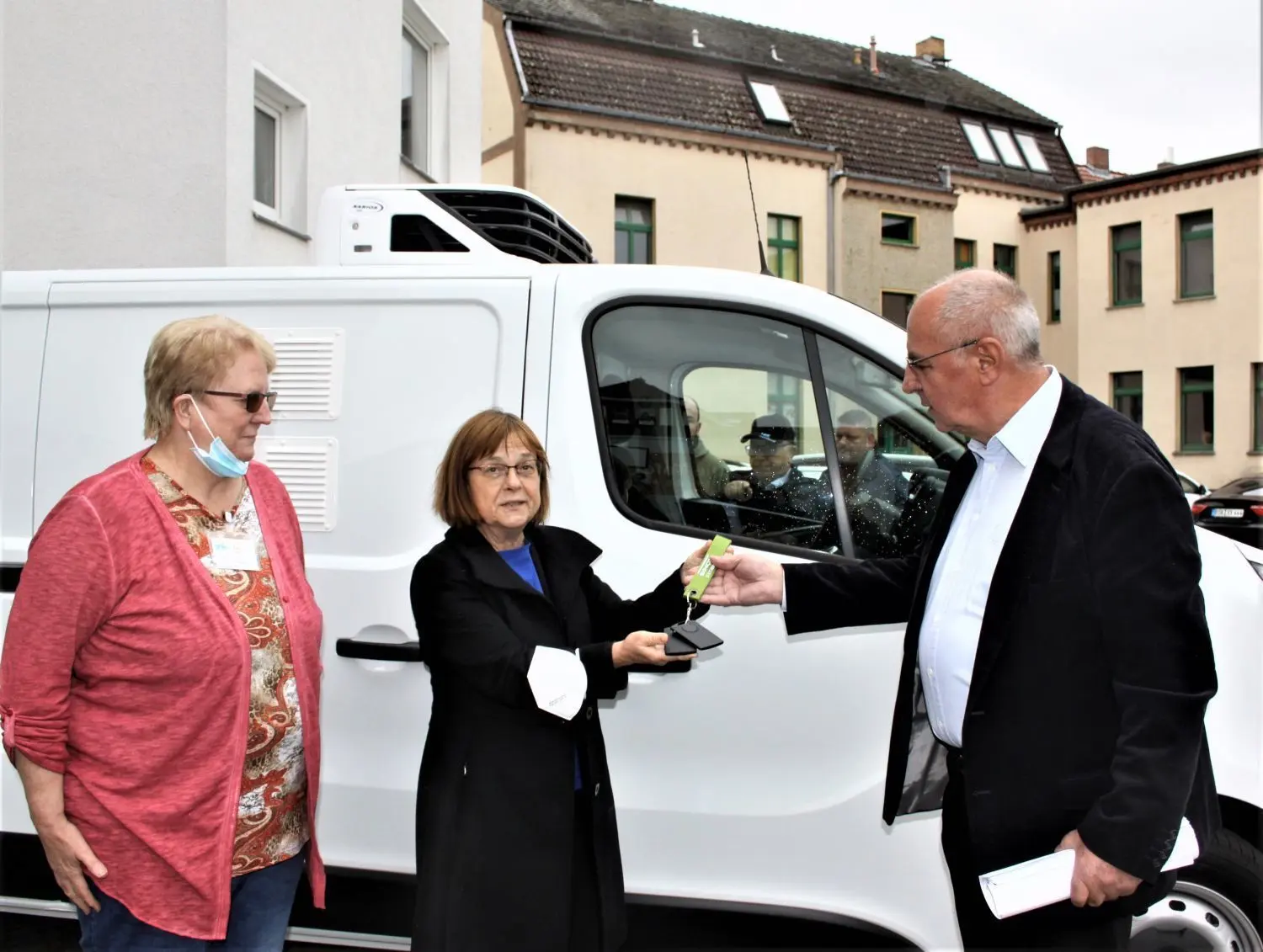 Brandenburgs Sozialministerin Ursula Nonnemacher übergibt die Fahrzeugschlüssel für ein neues Kühlfahrzeug an Siegfried Unger, Vorstand der Gesellschaft für Arbeit und Soziales (Gefas), auf dem Hof der Tafel Beeskow. Marita Schwarz (l.), Leiterin der Einrichtung, ist sichtlich erfreut.