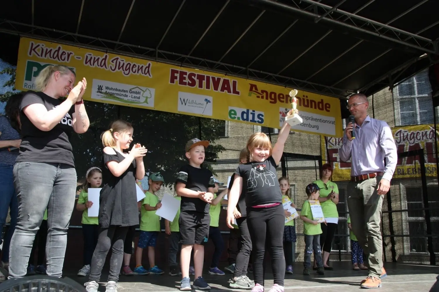 Kinder- und Jugendfestival Angermünde: Zum zweiten Mal kam das größte Talentefestival Brandenburgs und Berlins in die Uckermark und bot Kindern und Jugendlichen eine große Bühne. Bürgermeister Frederik Bewer (r.) stiftete für alle Teilnehmer Pokale, hier für die Kita Kerkow.