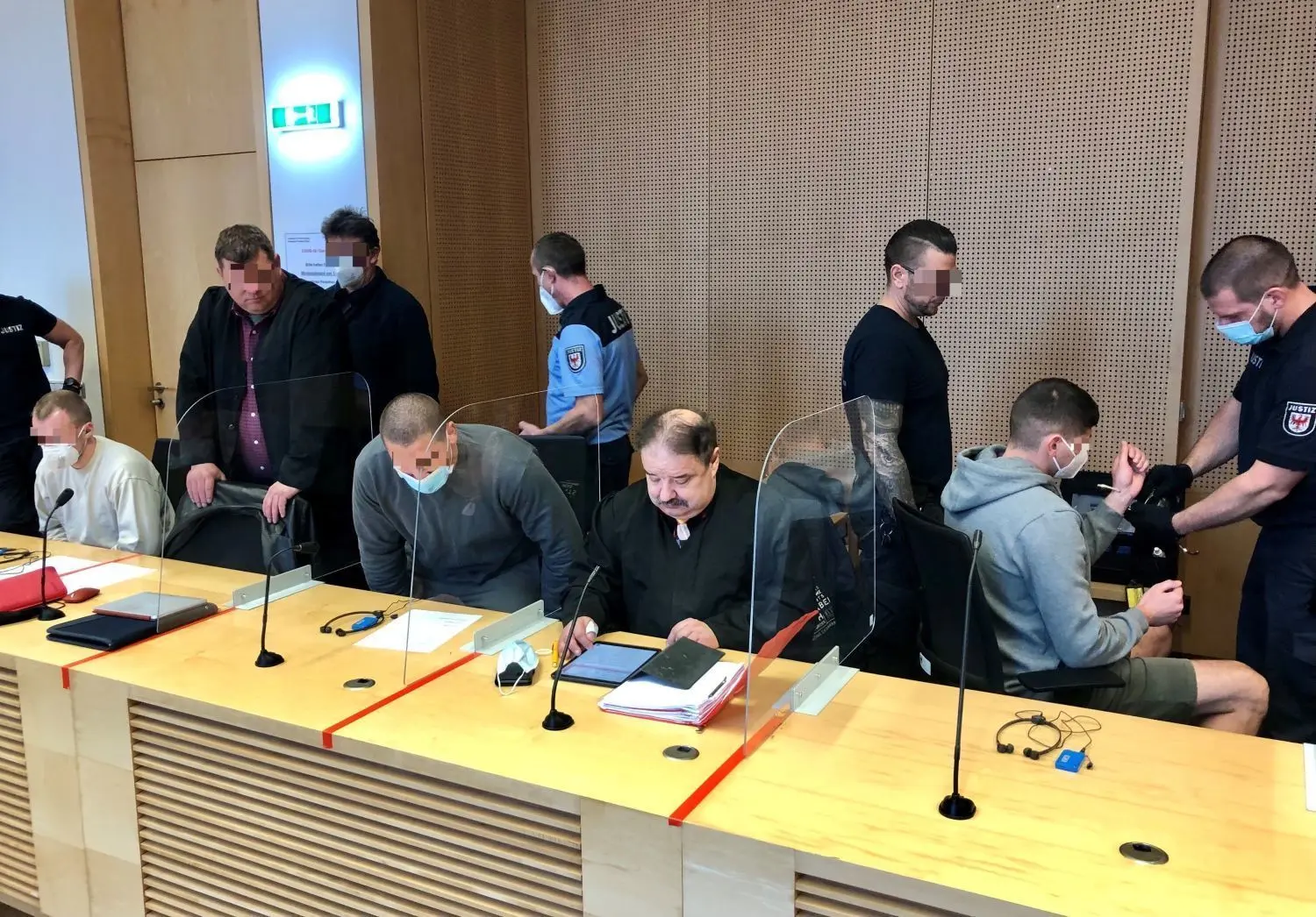 Sollen teure Autos im Berliner Speckgürtel gestohlen haben: Die drei belarussischen Angeklagten (sitzend mit Maske) mit ihren Verteidigern und Justizbeamten kurz vor Beginn der Verhandlung am Frankfurter Landgericht