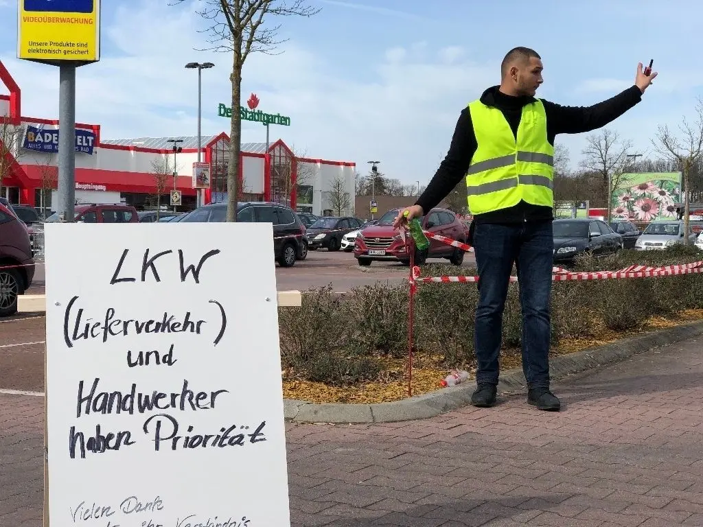 Ein Mitarbeiter der Bauhaus-Filiale in Birkenwerder regelt den Verkehr auf dem Parkplatz. Dort dürfen seit Mitwocch nur noch 150 bis 160 Privatkunden parken. So soll die Kundendichte reduziert werden.