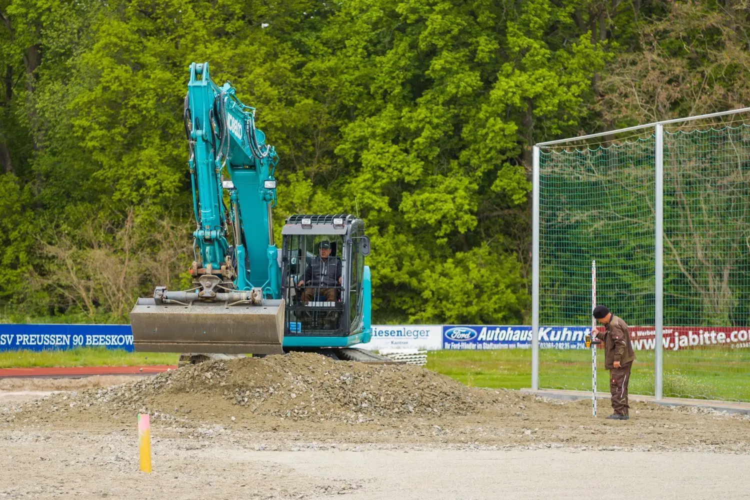 Michael Görsdorf und Abedin Hoxha (r.) bringen den Unterbau für die Weitsprunganlage am Südende des Fußballfeldes ein.
