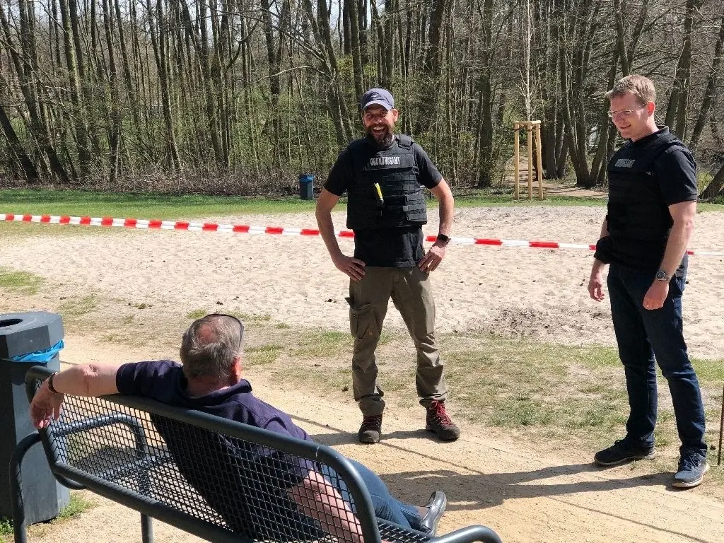 Kurze Pause: Die Absperrmaßnahmen am Briesesee werden von den zahlreichen Spaziergängern am Karfreitag respektiert. Das kurze Ausruhen auf einer Bank wird von Stephan Beyer (l.) und Martin Hafemann vom Ordnungsamt toleriert.
