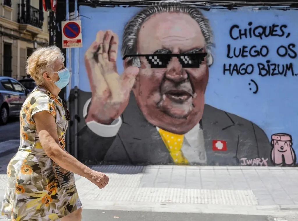 Eine Frau geht an einem Graffiti des Künstlers J.Warx in Valencia vorbei, das den Altkönig Juan Carlos neben der Aufschrift „Jungs, ihr bekommt später eine Überweisung“ darstellt. Der von einem Korruptionsskandal und von Justizermittlungen bedrängte spanische Ex-König Juan Carlos soll sein Land schon vor der amtlichen Ankündigung seiner Auswanderung heimlich verlassen haben.