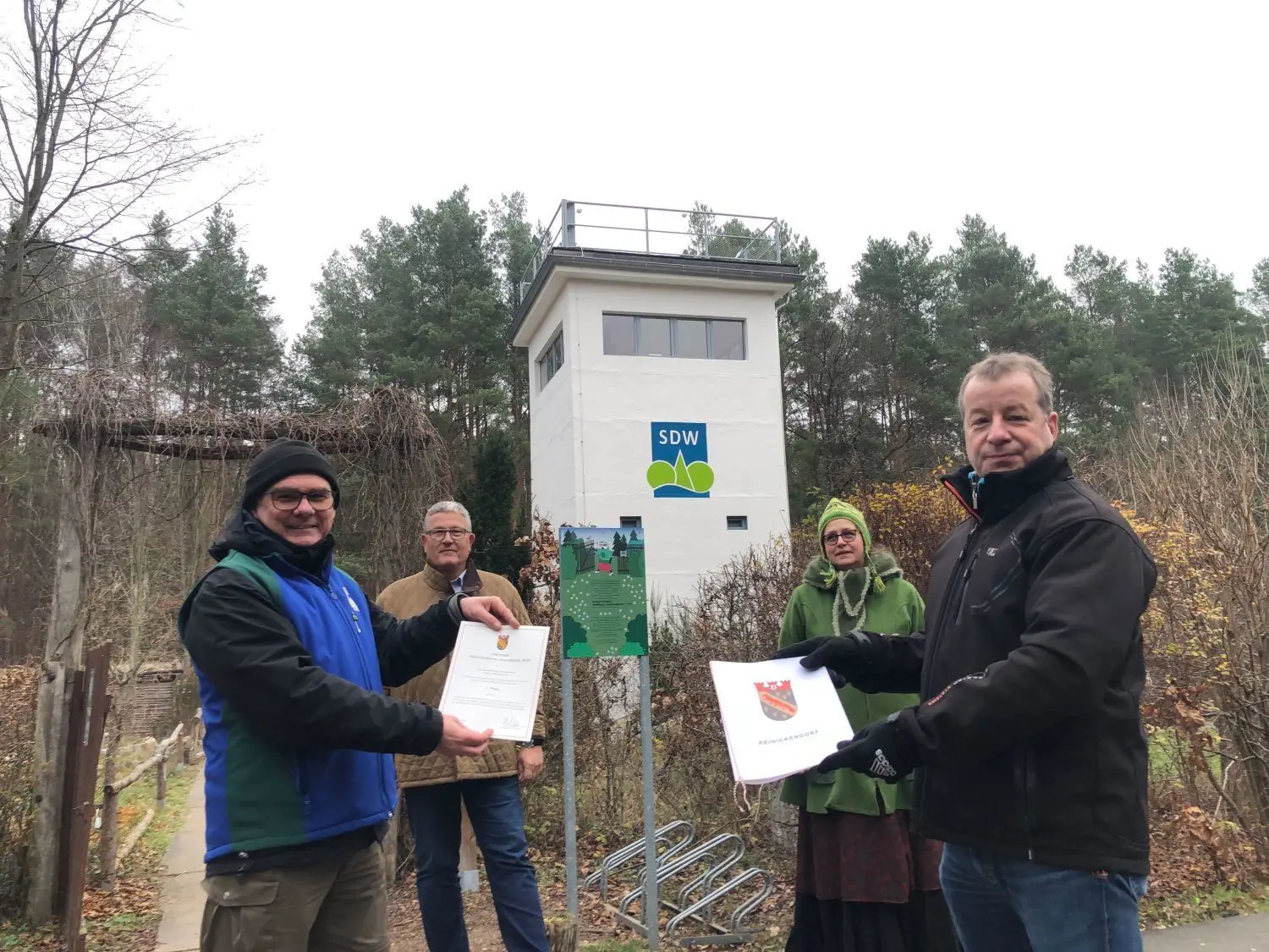 Reinickendorfs Bezirksbürgermeister Frank Balzer (r.) überreicht vor dem Naturschutzturm an Reinhard Bergmann (l.) vom Vorstand des Regionalverbandes Oberhavel der Schutzgemeinschaft Deutscher Wald die Urkunde. Der Zeremonie wohnten auch Naturpädagogin Friederike Blenau und der Leiter des Berliner Forstamtes, Karl-Heinz Marx, als Vereinsmitglieder bei.
