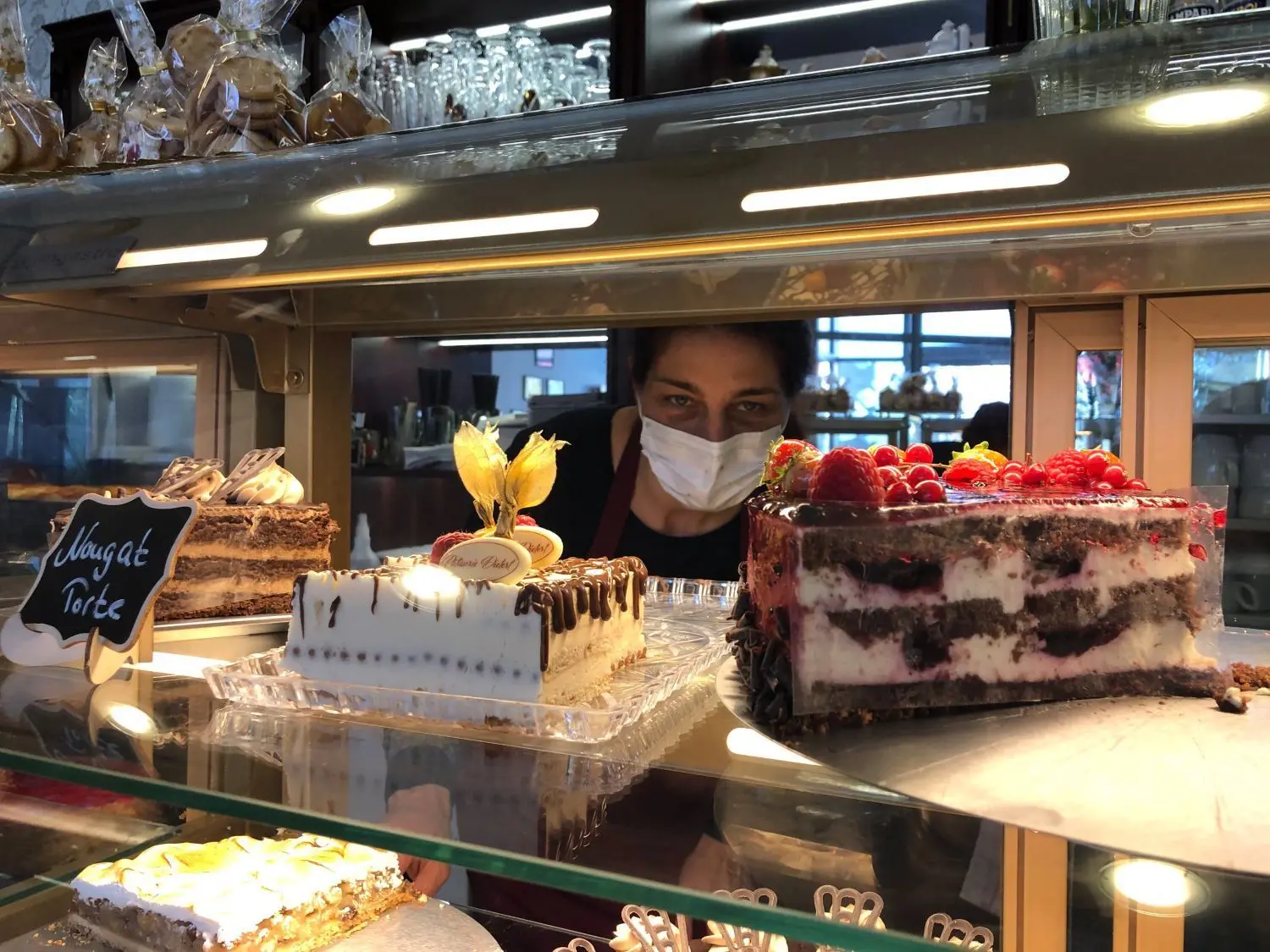 Tanja Dietert blickt durch die Tortenauslage in ihrer Patisserie. Neben Süßem gibt es dort auch einen deftigen Mittagstisch – natürlich zum Mitnehmen.