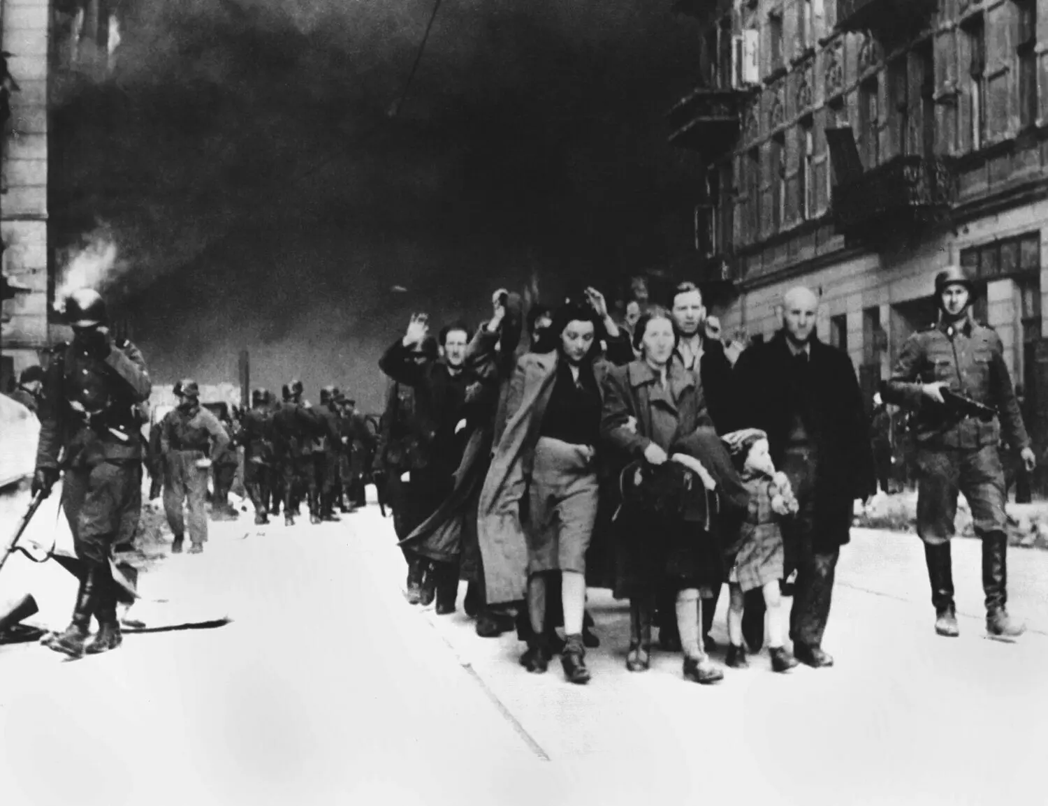 Warschau, 30. April 1943: Mit erhobenen Händen werden jüdische Frauen, Männer und Kinder von deutschen SS-Soldaten aus dem brennenden Ghetto der polnischen Hauptstadt Warschau getrieben.