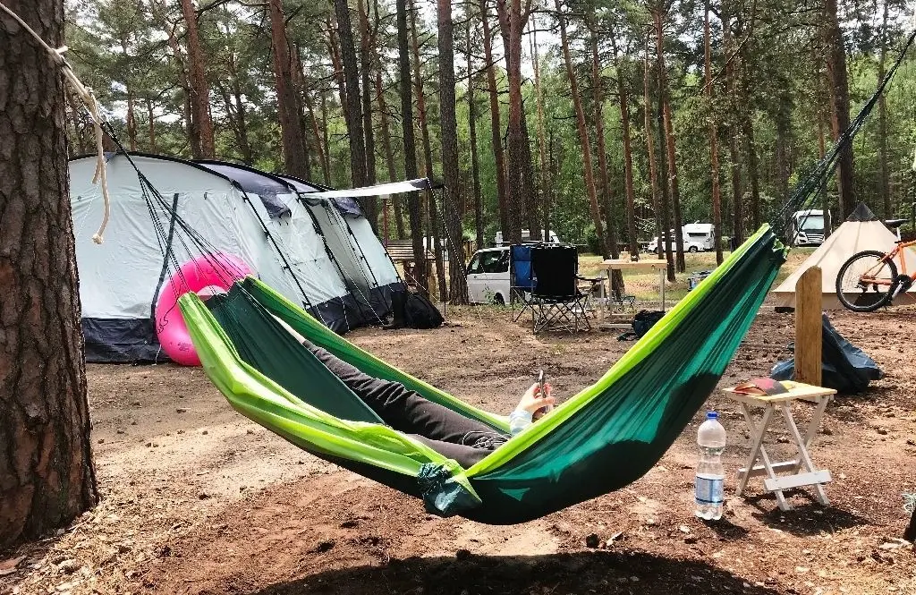 Eine Camperin entspannt mit WLAN in der Hängematte auf dem Zeltplatz.