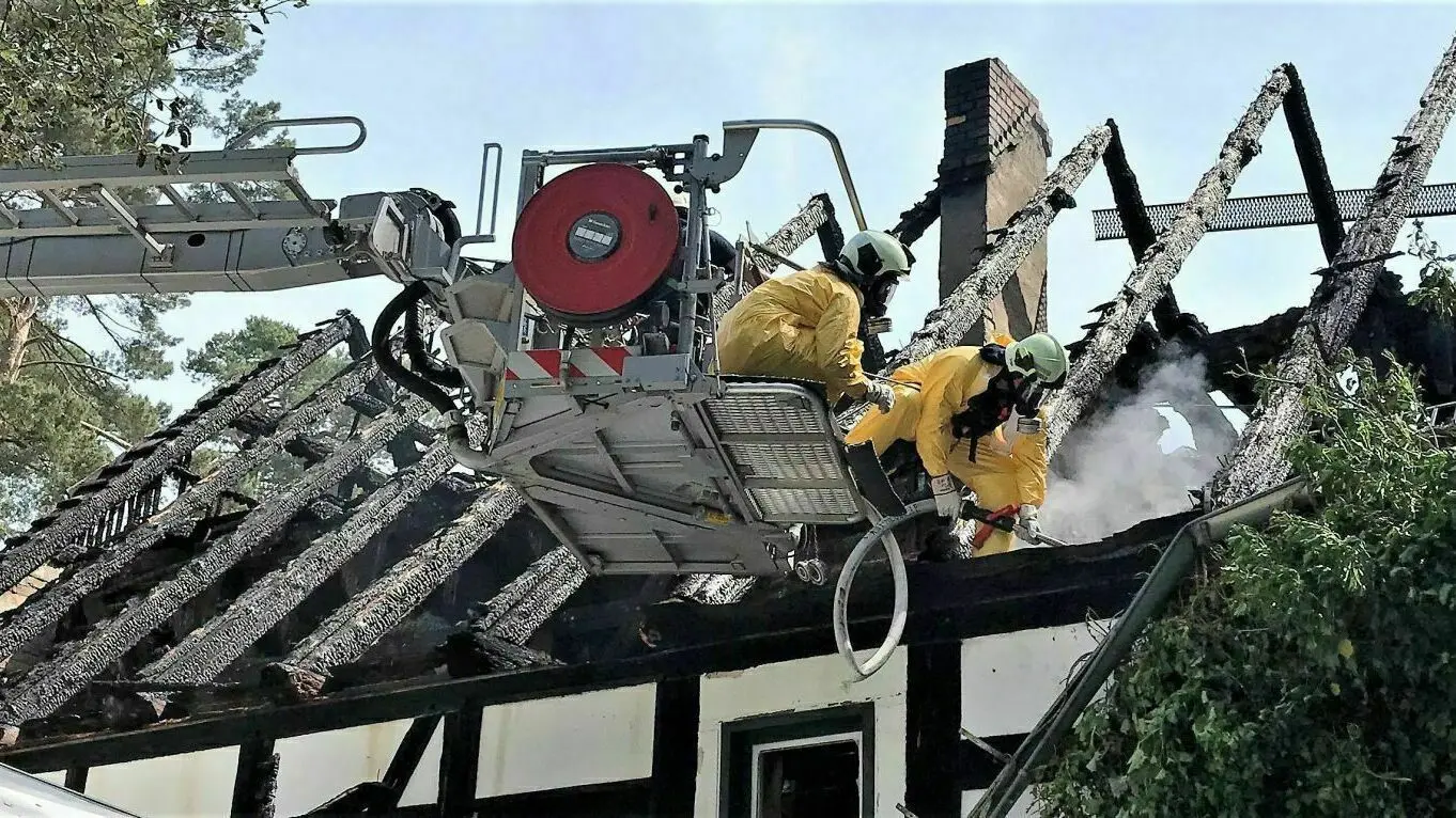Spezialkräfte: Höhenretter der Werkfeuerwehr von ArcelorMittal Eisenhüttenstadt versuchen mit einer Löschlanze, Glutnester im Dachgebälk zu löschen.