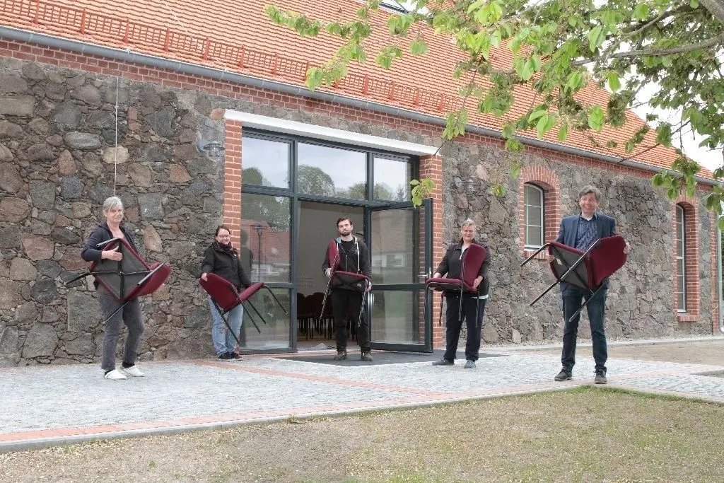 Nur Stühle fehlen noch: Darius Müller (r.) und ein Teil des Schloss-Teams vor der sanierten Feldsteinscheune in Trebnitz