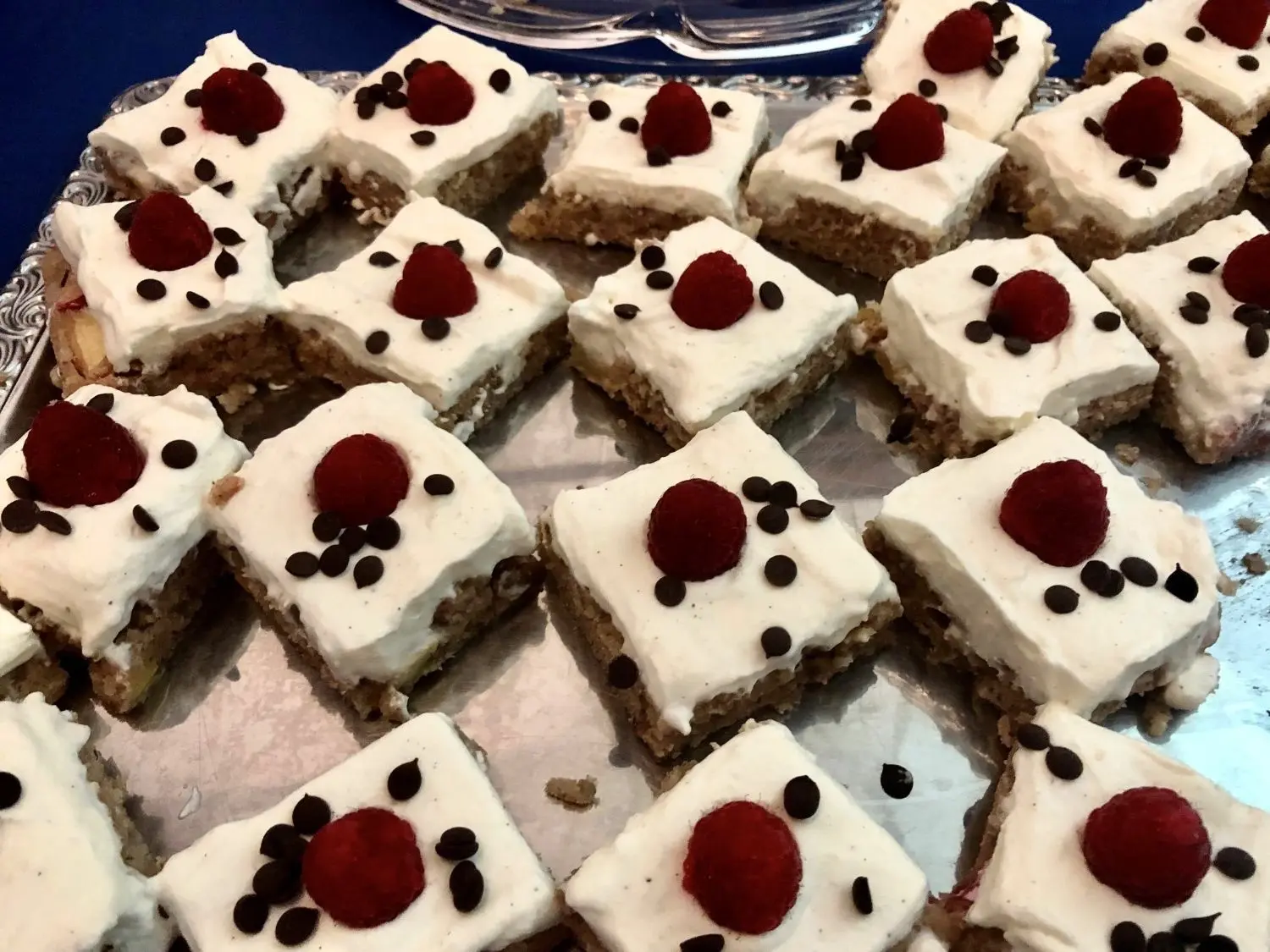 Nusskuchen mit Apfel, Schlagsahne, obendrauf thront eine Himbeere.