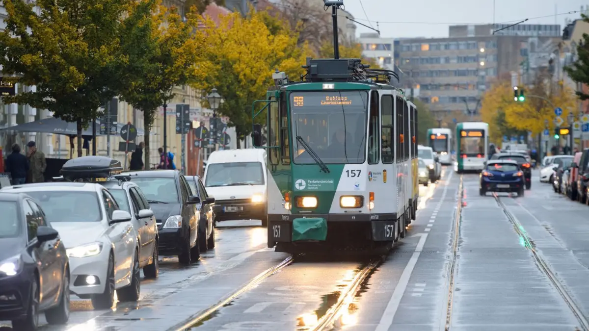 Eine Straßenbahn der Linie 98 zum Schloss Cecilienhof fährt auf der regennassen Charlottenstraße in Potsdam an den vor einer roten Ampel wartenden Autos vorbei.
Eine Straßenbahn der Linie 98 zum Schloss Cecilienhof fährt auf der regennassen in der Charlottenstraße an den vor einer roten Ampel wartenden Autos vorbei.