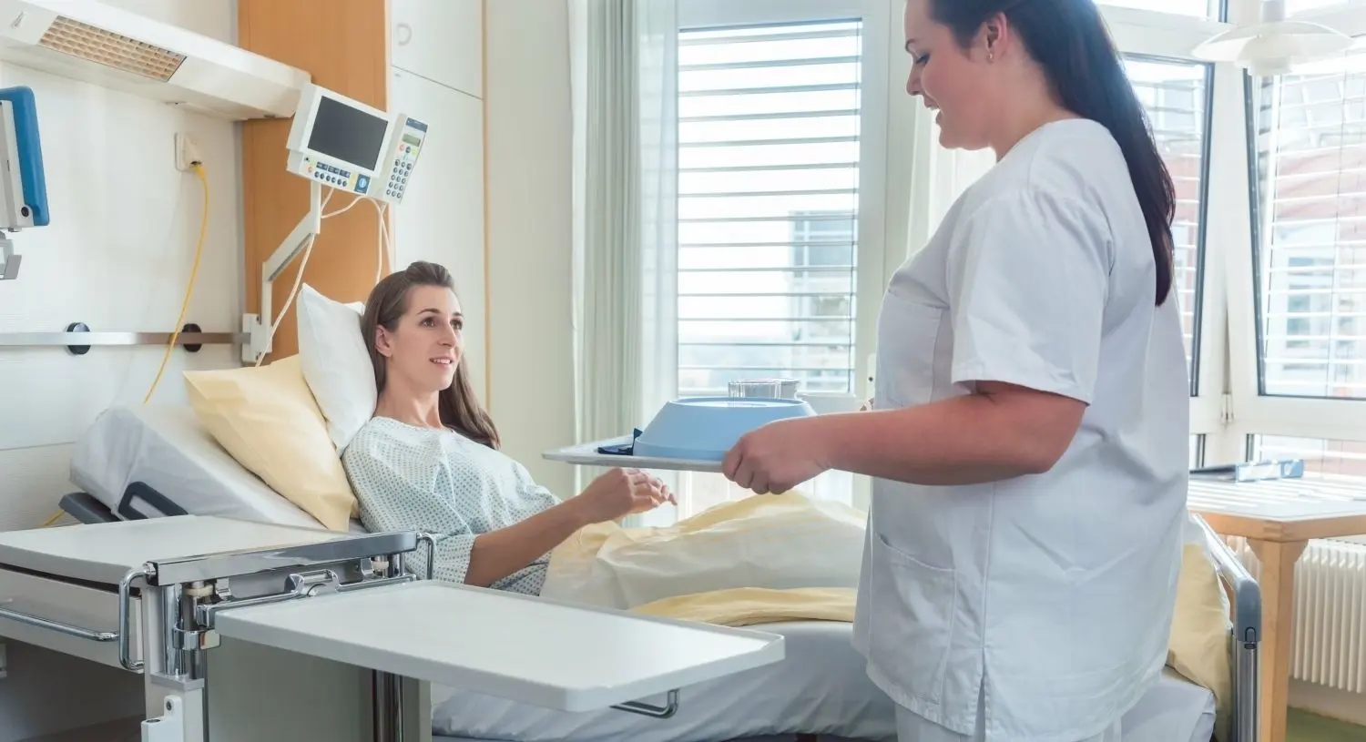 Eine Krankenschwester bringt einer Patienten in der Klinik das Mittagessen.