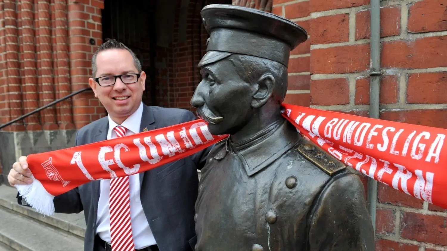 Oliver Igel, Bezirksbürgermeister von Treptow-Köpenick, ist natürlich auch Fan des 1. FC Union Berlin. Hier posiert der 43 Jahre alte SPD-Politiker mit Fan-Schal neben der Figur des Hauptmanns von Köpenick.