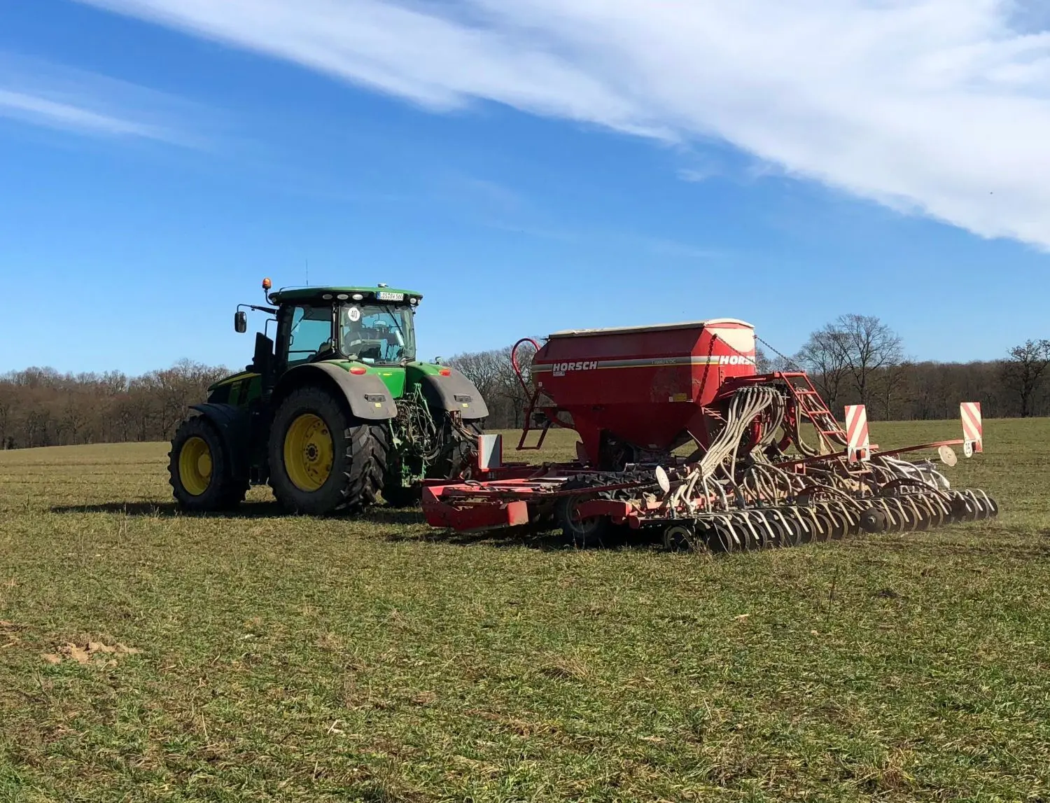 Säen statt schleudern: Der Traktor fährt mit der Drillmaschine im Schlepptau über den schon bestellten Acker.