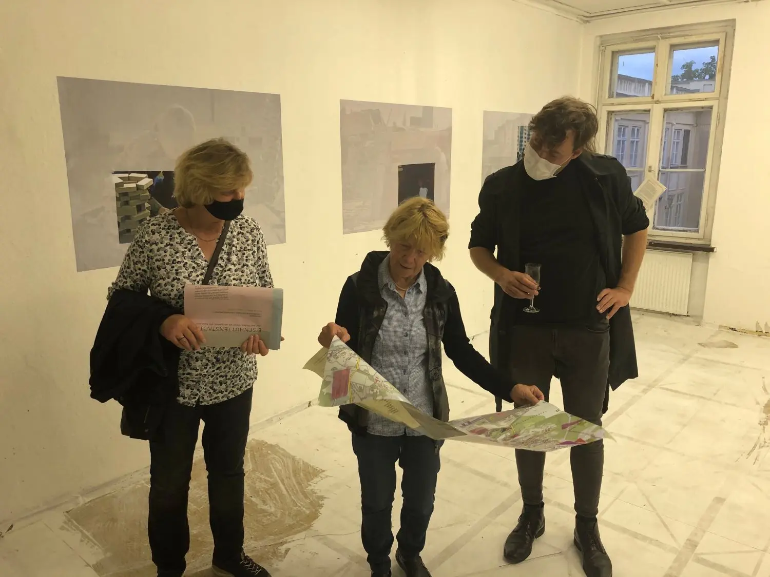 Erkundungen: Heike Gunkel, Sieglinde Wischnewski und Michael Hirschbichler schauen sich den Stadtplan von Natalie Obert an, die auf Grundlage von Gesprächen mit Eisenhüttenstädtern Lieblingsorte verzeichnet hat. Im Hintergrund sind Arbeiten von Anne Schülke zu sehen.