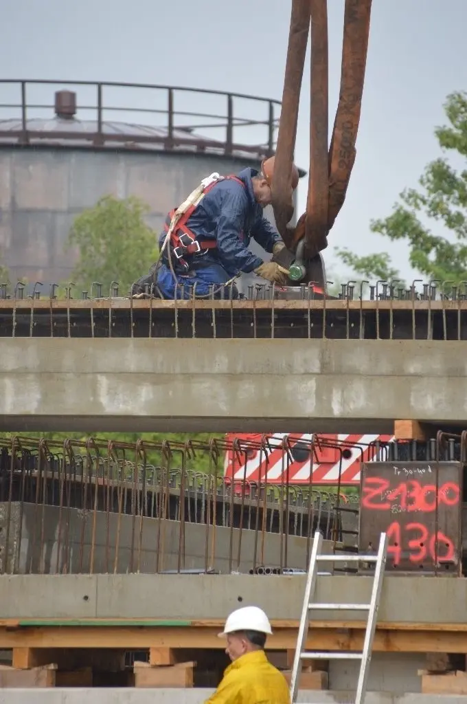 Mit Sicherheitsgurt: Ein Monteur verschraubt den Schäkel für den Tandemhub.