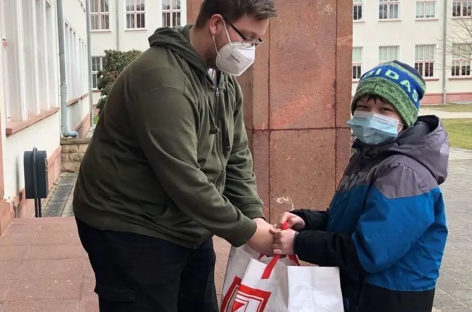 Übergabe an der Schule: Karl (10) übergibt eine Einkaufstasche voller Lebensmittel für die Kinder in der Ukraine. Marc, ein Schüler der 12. Klasse der Gesamtschule in Eisenhüttenstadt, nimmt die Spende entgegen.