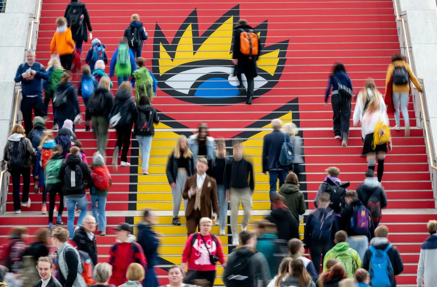27.04.2023, Sachsen, Leipzig: Besucher der Leipziger Buchmesse gehen zur Eröffnung über eine Treppe mit dem Logo der Buchmesse. Auf dem Frühjahrstreffen der Buchbranche präsentieren rund 2000 Aussteller aus 40 Ländern ihre Neuheiten rund ums Buch. Als Buchmesse-Gastland präsentiert sich Österreich.