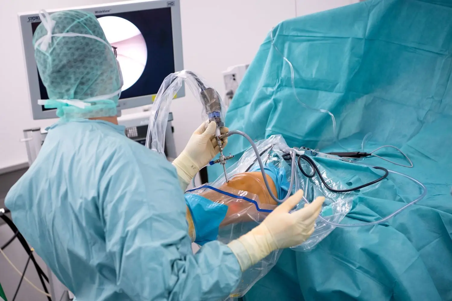 Inmitten der Operation: Ein Arzt operiert einen Patienten am Knie.