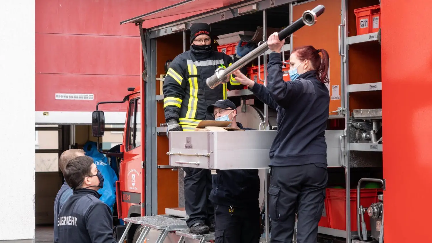 Die hauptamtlichen Kräfte unterstützen die Übung und reichen Einsatzmittel vom Fahrzeug.